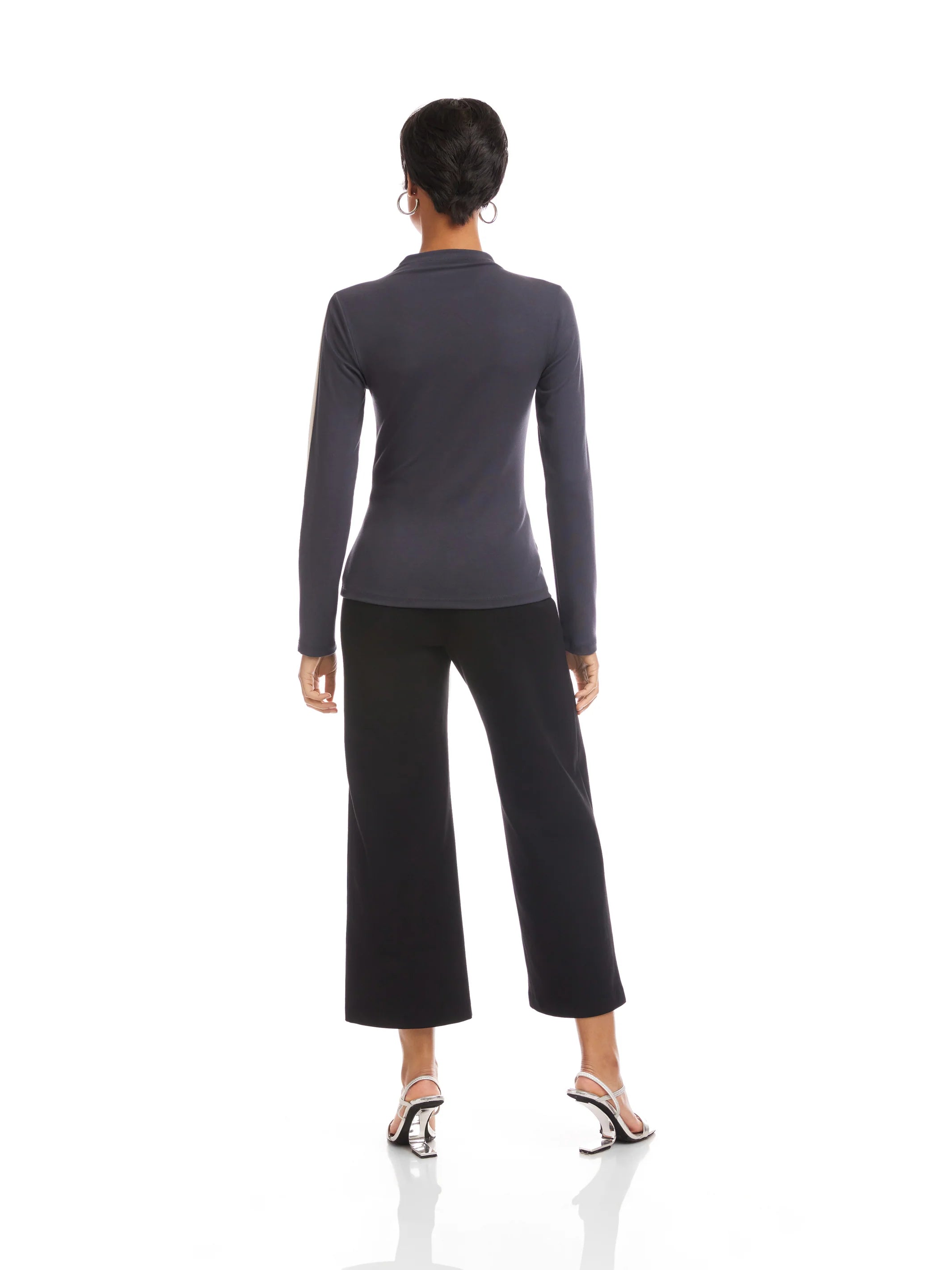 Woman wearing a gray long-sleeve top and black pants on a white background