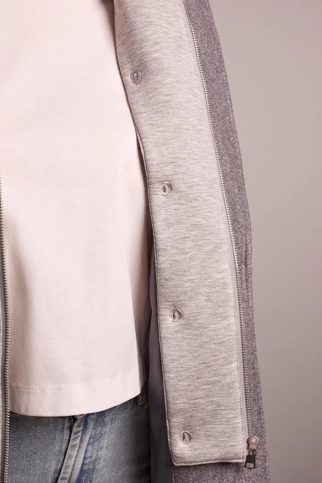 Close-up of a gray coat with a white shirt and jeans on a neutral background