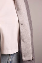 Close-up of a gray coat with a white shirt and jeans on a neutral background