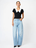 Woman wearing a black top and light blue jeans on a white background