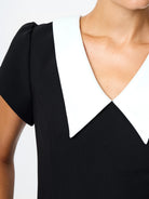 Black dress with a white collar on a plain background