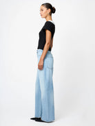 Woman wearing light blue jeans and a black top on a white background