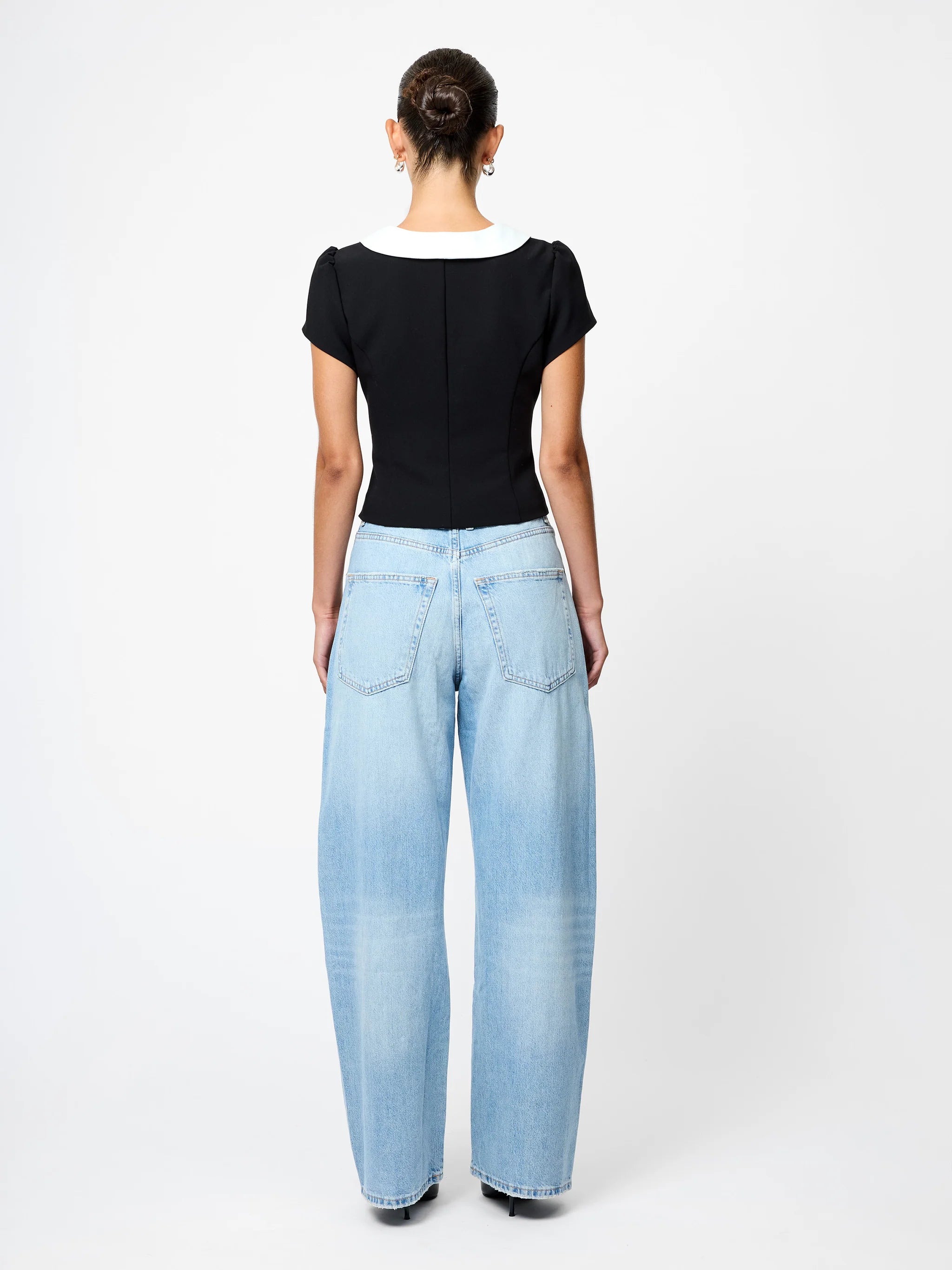 Person wearing light blue jeans and a black top on a white background