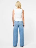 Person wearing light blue jeans and a white sleeveless top on a white background