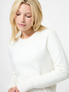 Woman wearing a white sweater against a plain background
