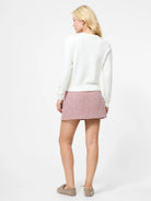 Person wearing a white sweater and pink skirt on a white background