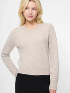 Woman wearing a beige sweater against a white background