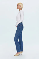 Woman wearing blue jeans and a white top on a light gray background