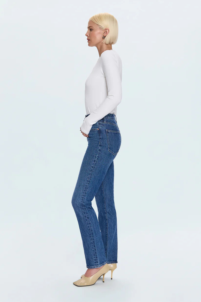 Woman wearing blue jeans and a white top on a light gray background