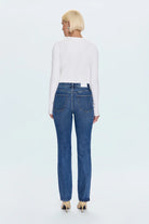 Person wearing blue jeans and a white top on a light blue background