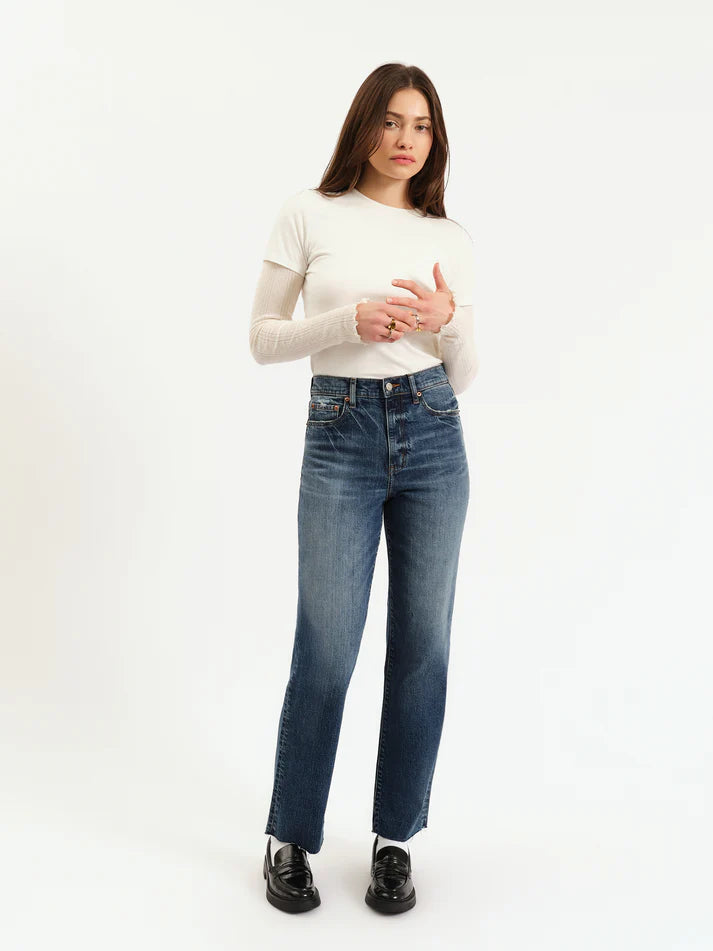 Woman wearing blue jeans and a white top on a white background