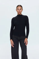 Person wearing a black turtleneck sweater and dark jeans on a white background