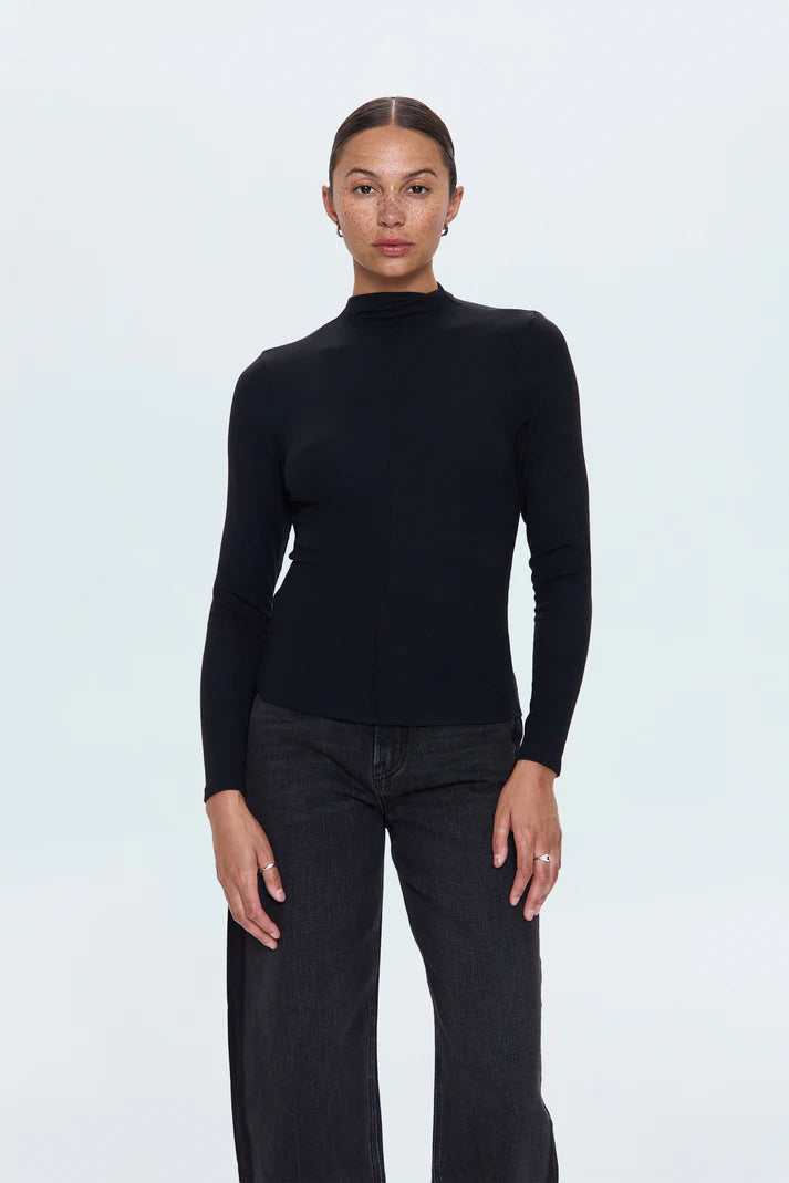 Person wearing a black turtleneck sweater and dark jeans on a white background