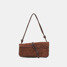 Brown suede handbag with a strap on a light gray background