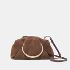 Brown suede handbag with gold circular handle on a light gray background