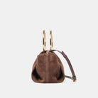 Brown suede handbag with gold handles on a light gray background