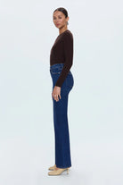 Woman wearing a brown top and blue jeans on a white background