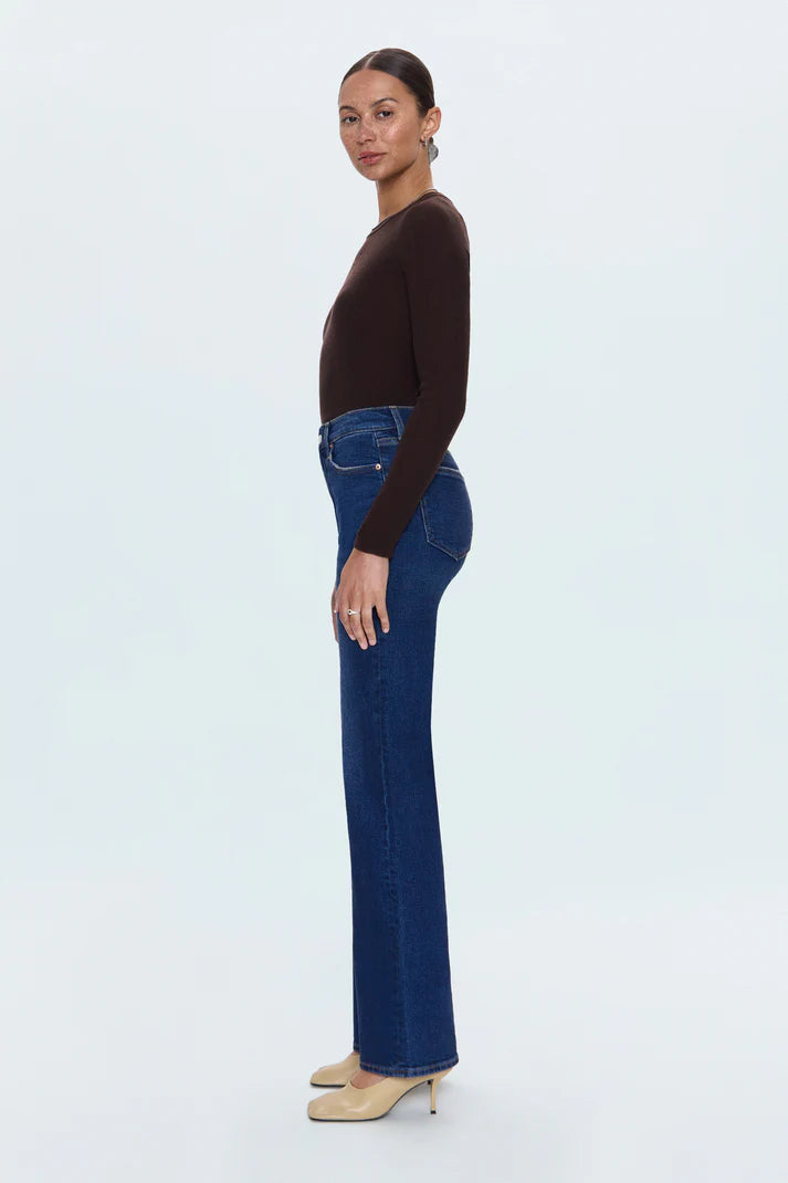 Woman wearing a brown top and blue jeans on a white background