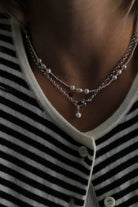 Close-up of a person wearing a layered necklace with a striped shirt.