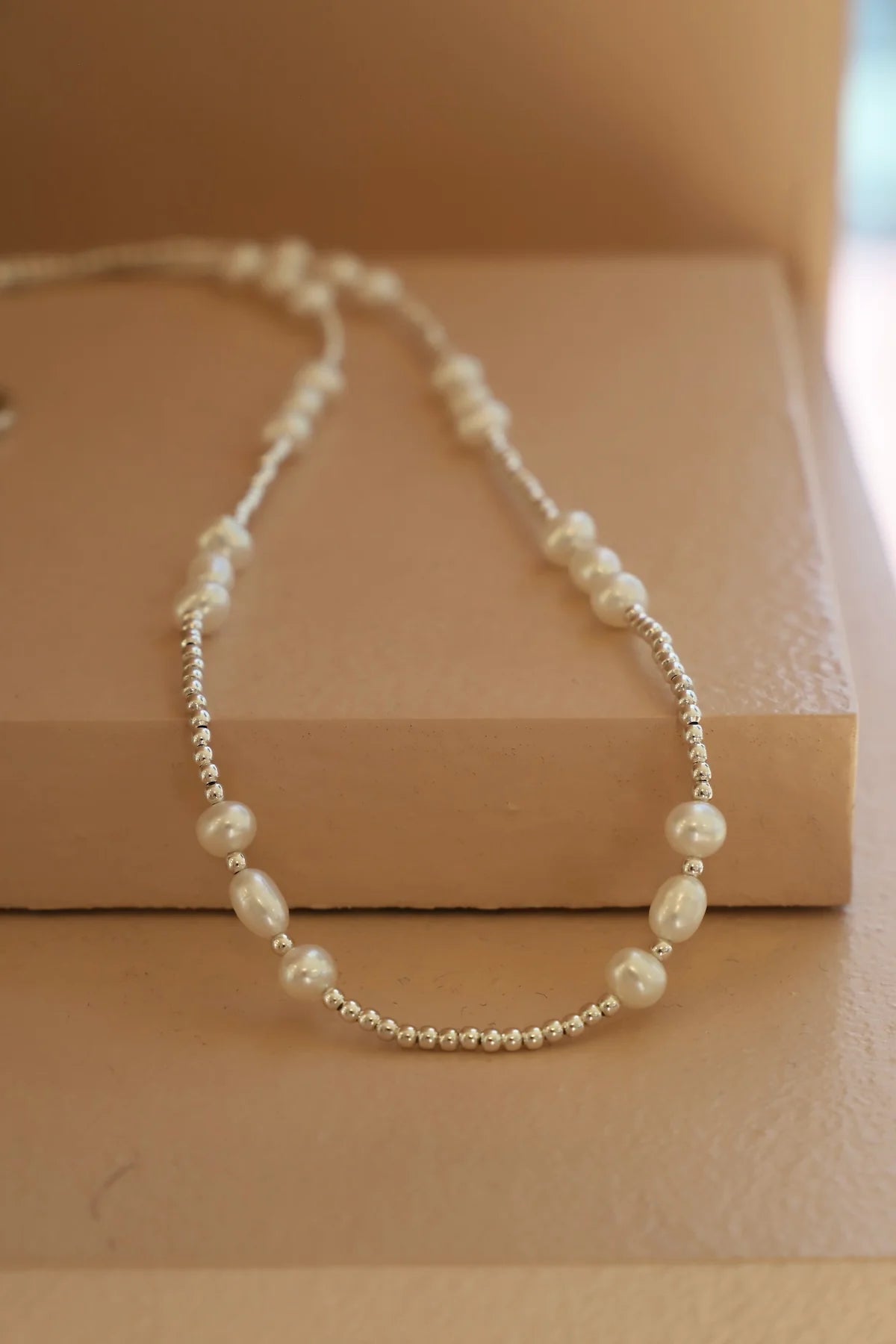 Pearl necklace on a beige surface