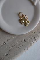 Gold heart-shaped earrings on a white plate