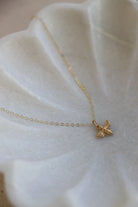 Gold necklace with a bee pendant on a white fabric background