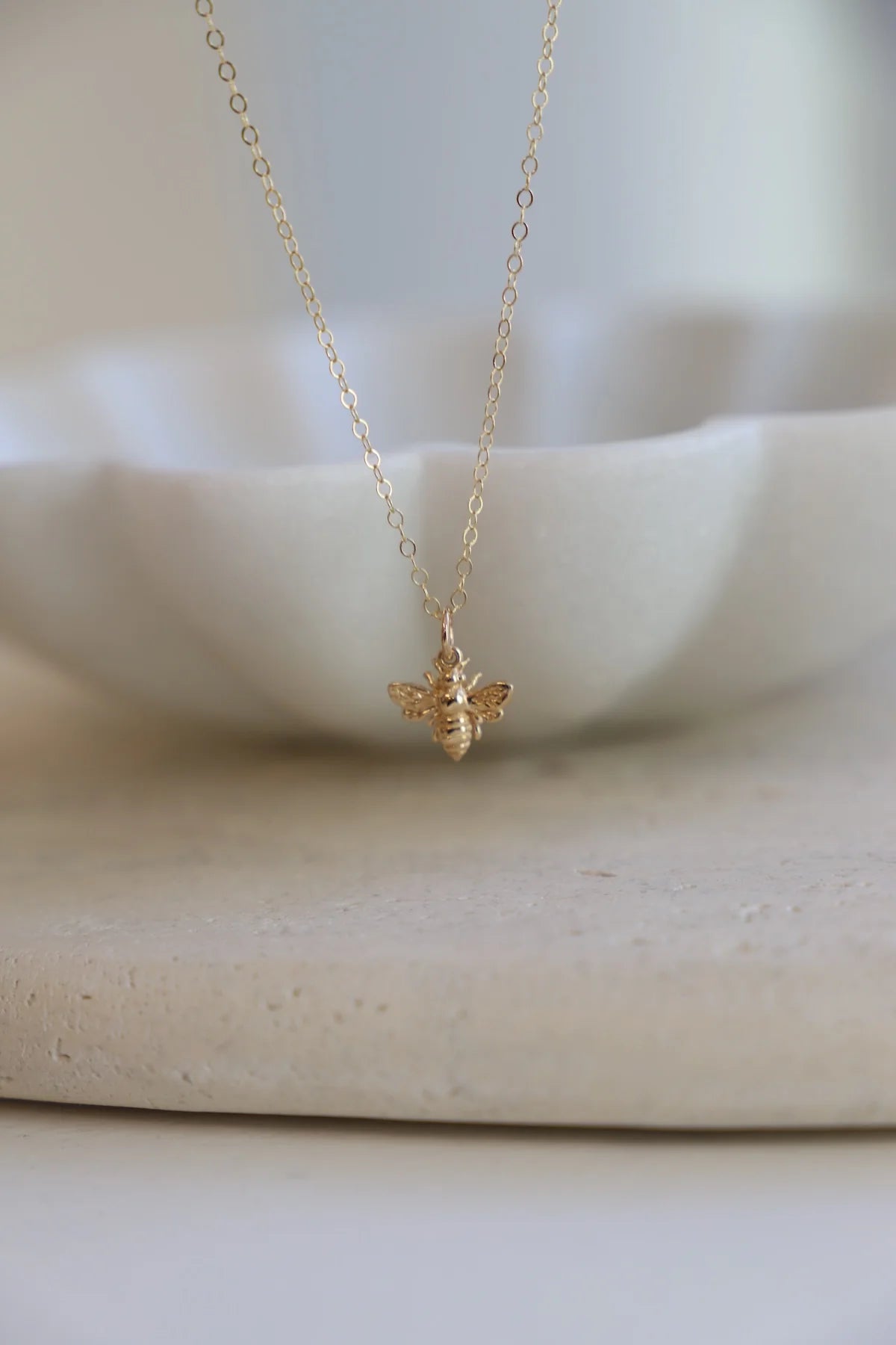 Gold bee necklace on a white background