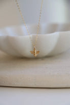Gold bee necklace on a white dish