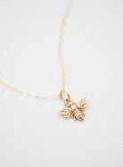 Gold bee necklace on a white background