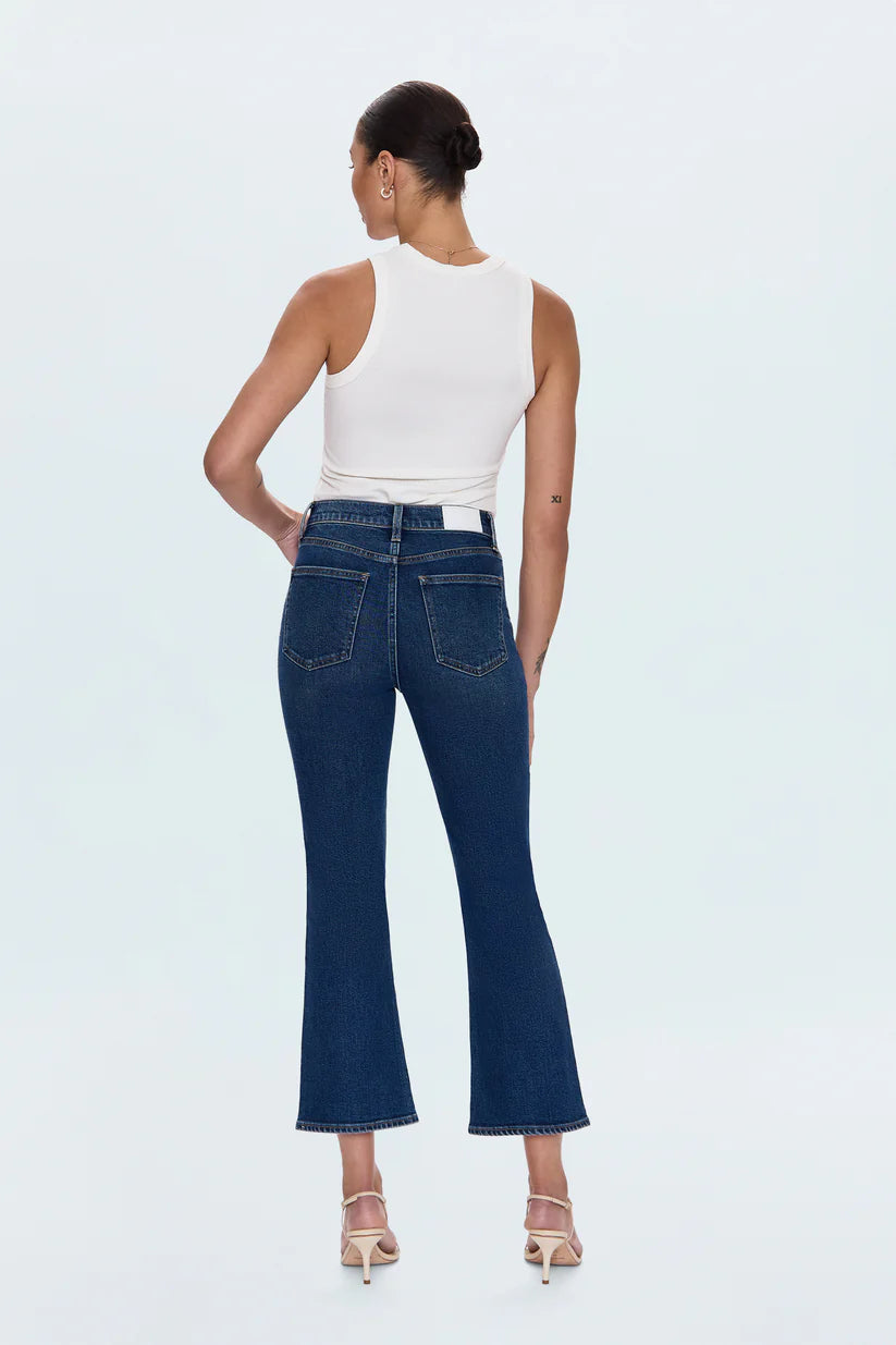 Woman wearing blue jeans and a white top on a light gray background