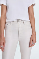 Person wearing light gray jeans and a white top on a light blue background