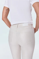 Person wearing light-colored pants and a white top on a plain background