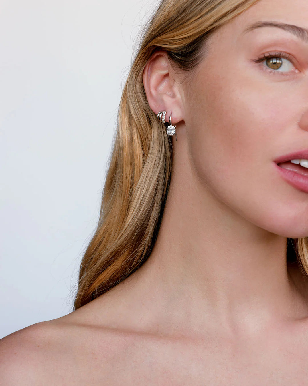 Close-up of a woman wearing diamond earrings with a plain background