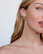Close-up of a woman wearing diamond earrings with a plain background