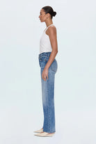 Woman wearing blue jeans and a white top on a light blue background