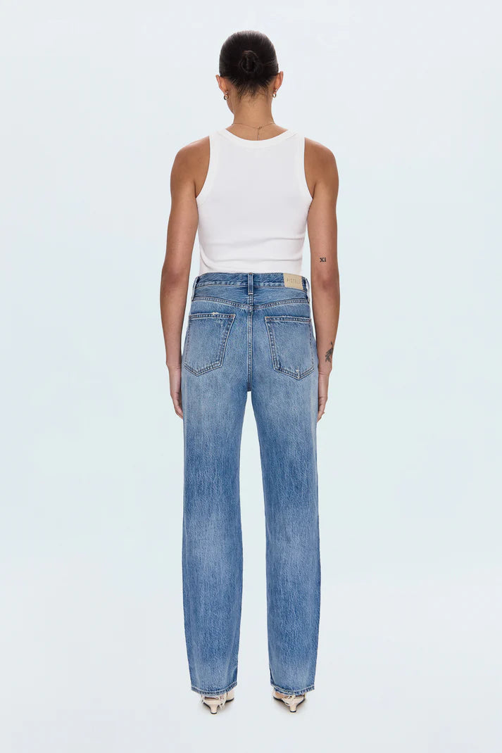 Person wearing blue jeans and a white tank top on a light gray background