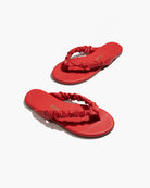 Red sandals with ruched straps on a white background