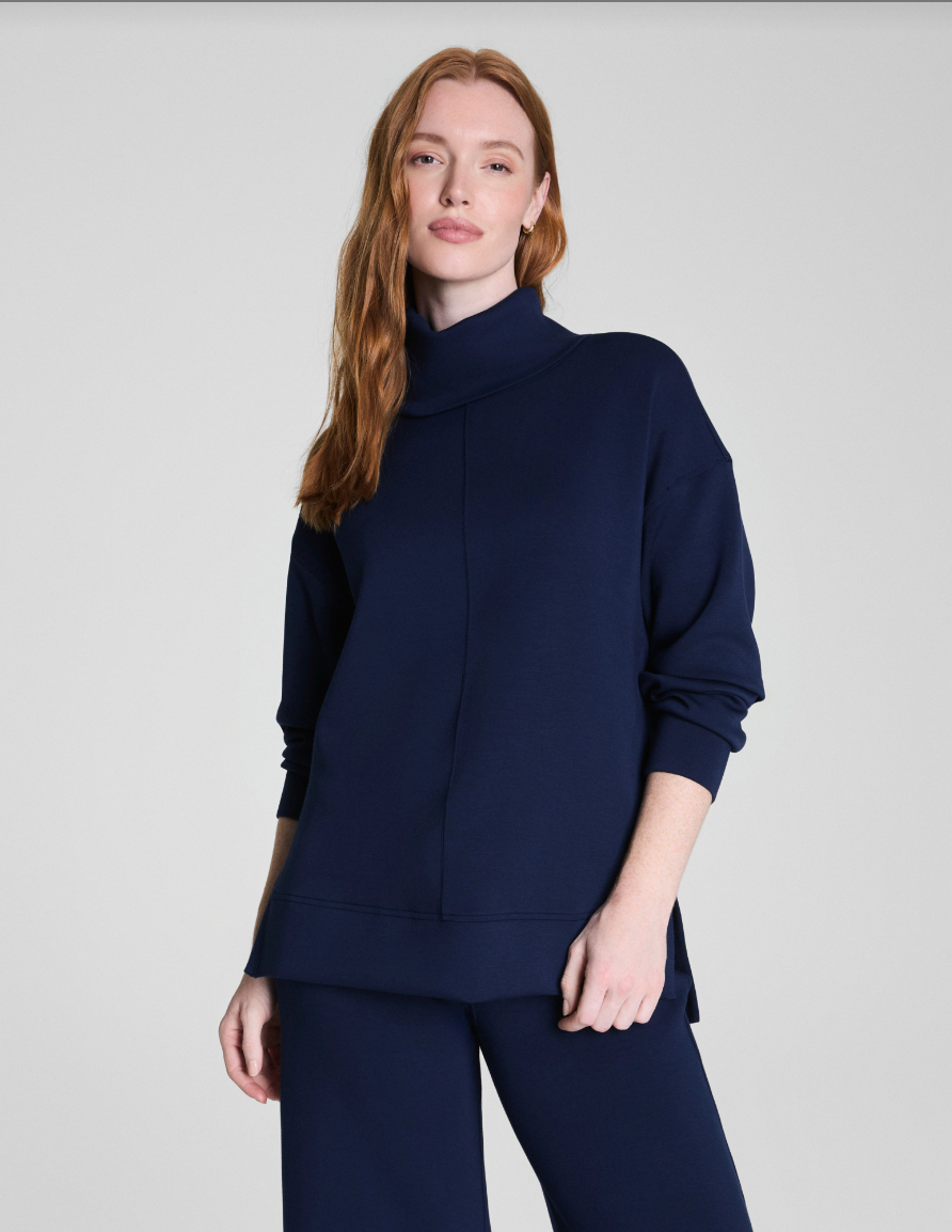 Woman wearing a navy blue sweater and pants on a light gray background