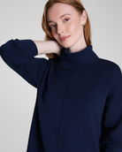 Woman wearing a navy blue sweater against a plain background
