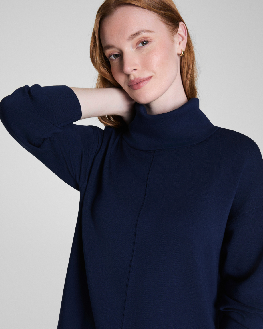 Woman wearing a navy blue sweater against a plain background