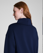 Person wearing a navy blue coat on a plain background