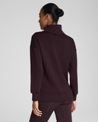 Person wearing a dark brown turtleneck sweater on a light gray background