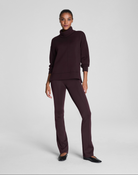 Woman wearing a dark brown turtleneck sweater and pants on a white background