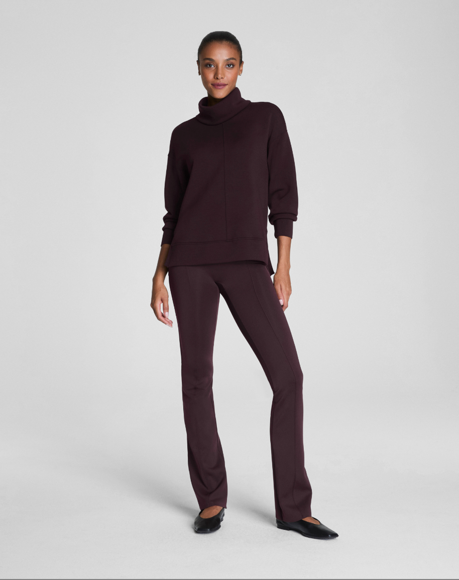 Woman wearing a dark brown turtleneck sweater and pants on a white background