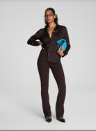 Woman wearing a black outfit holding a blue clutch against a white background