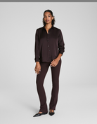 Woman wearing a dark brown shirt and pants on a white background