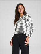Woman wearing a black and white striped long-sleeve shirt against a plain background