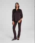 Woman wearing a dark brown shirt and pants on a white background