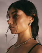 Woman wearing a necklace and earring against a neutral background