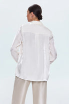 Person wearing a white blouse with lace details on a light blue background